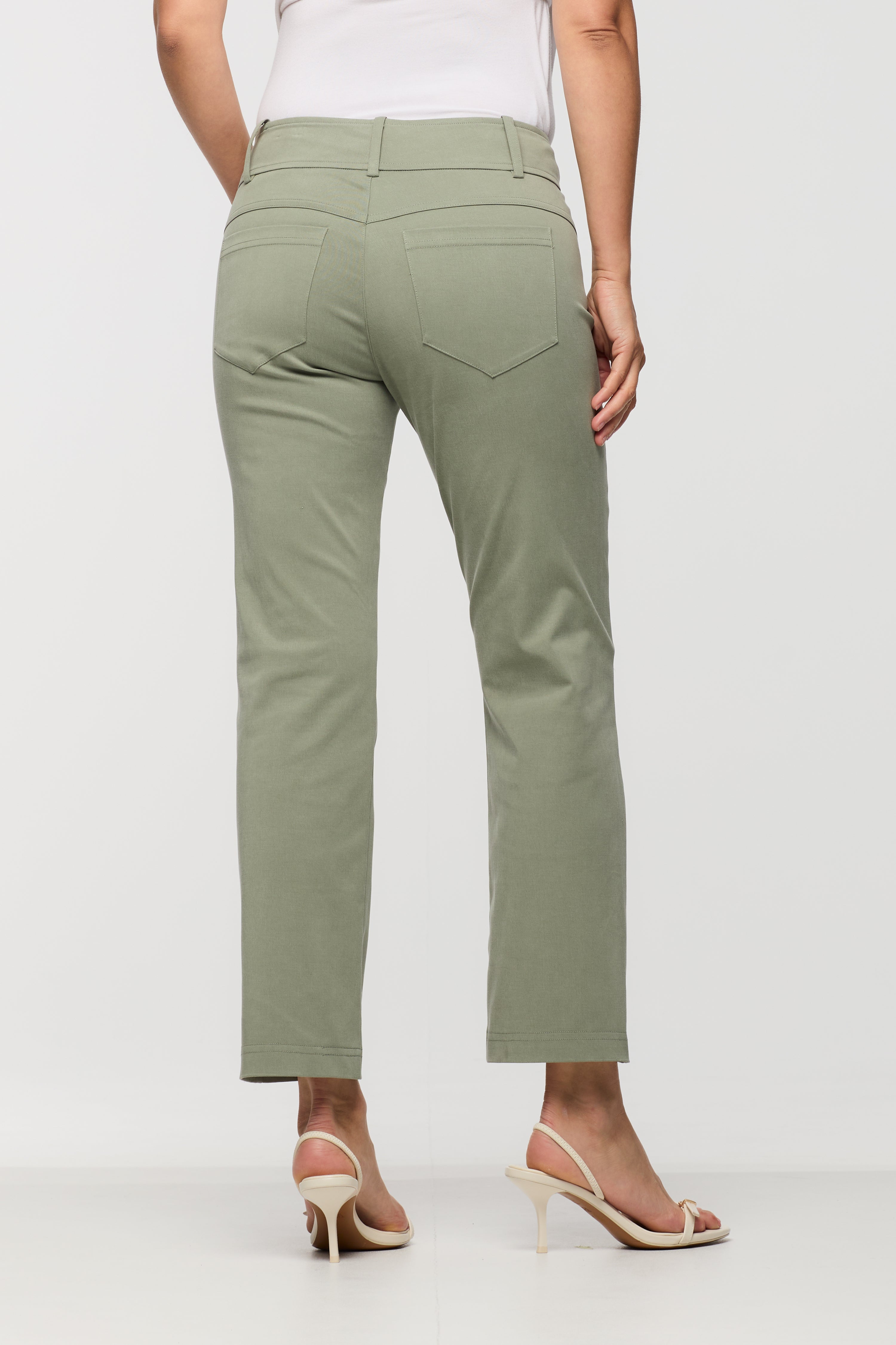 Woman wearing sage green cropped straight leg pants shown from the back, featuring belt loops and back patch pockets.