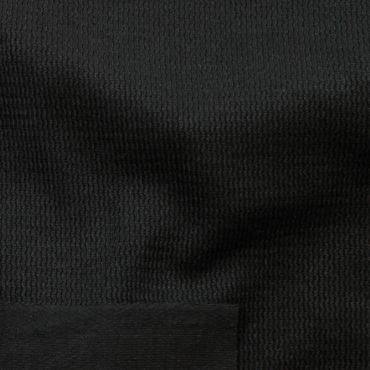 Close-up of a black ribbed knit fabric texture with a solid black horizontal band at the bottom.